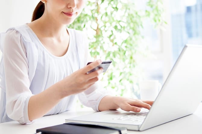 ノートPCを操作しながらクレジットカードを確認する人物